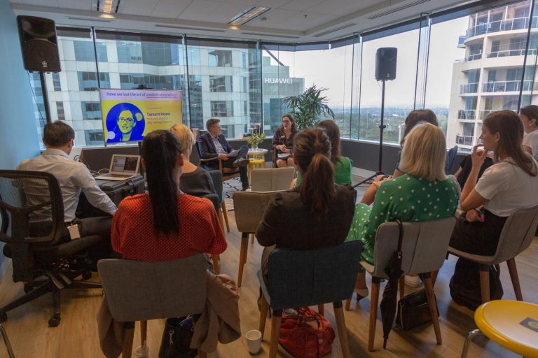 A group of people sitting listening to two people speaking